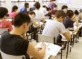 Estudantes sentados em carteiras escolares realizam as provas do Enem em uma sala de aula