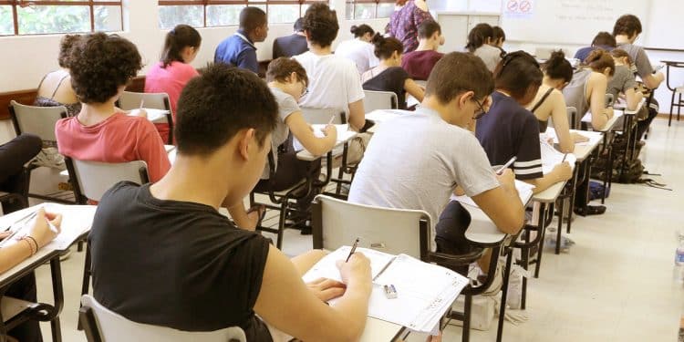 Estudantes sentados em carteiras escolares realizam as provas do Enem em uma sala de aula