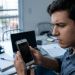 Homem observa o celular com expressão preocupada
