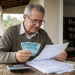 Aposentado segura notas de dinheiro e analisa extrato do INSS, em referência ao teto da Previdência de R$ 8.475,55 em 2026.