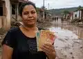 Mulher atingida por enchente segura notas de dinheiro em área destruída, representando os próximos repasses do Auxílio Reconstrução.