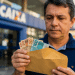 Homem em frente à agência da Caixa Econômica Federal segura envelope com dinheiro, em referência ao Saque Calamidade do FGTS liberado em 2026.