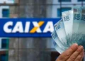 Pessoa segurando notas de cem reais em frente a uma agência da CAIXA, representando o saque de até R$ 6.220.