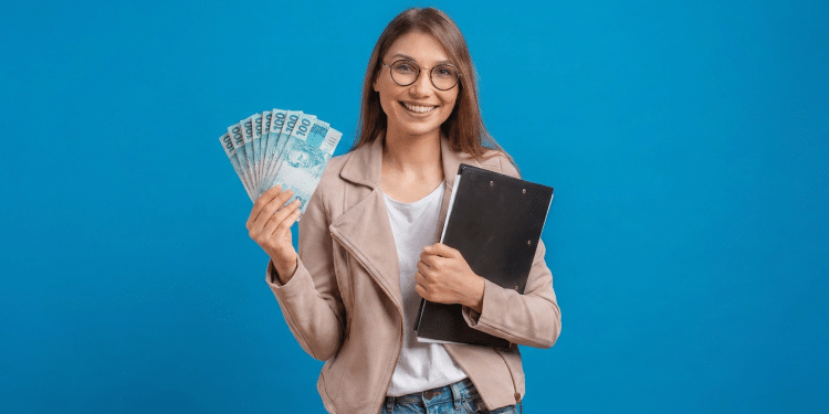 Jovem sorridente segurando notas de 100 reais e prancheta preta.