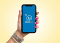 Aplicativo Caixa Tem exibido em smartphone com fundo amarelo.