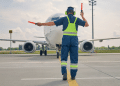Profissional guia avião comercial no pátio de aeroporto durante operação.