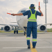 Profissional guia avião comercial no pátio de aeroporto durante operação.