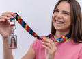 Jovem sorridente exibe crachá com cordão de peça de quebra-cabeça colorido.