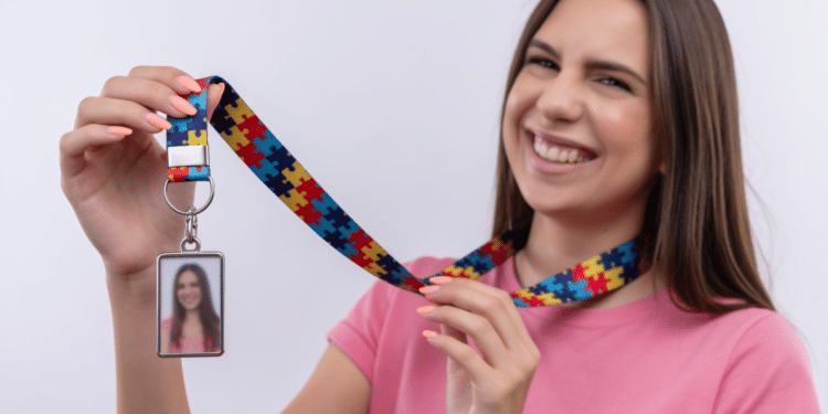 Jovem sorridente exibe crachá com cordão de peça de quebra-cabeça colorido.