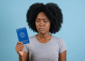 Jovem negra com expressão preocupada segura carteira de trabalho.