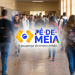 Grupo de adolescentes caminhando em corredor escolar com logo do Pé-de-Meia em destaque.
