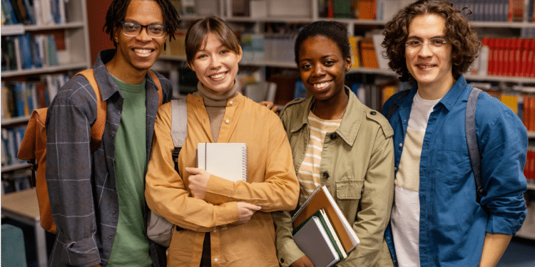 Grupo de estudantes sorrindo em biblioteca.