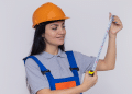 Profissional com trena e capacete laranja.