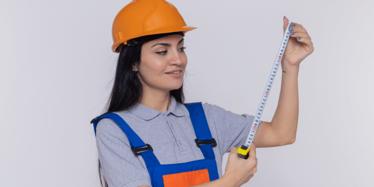 Profissional com trena e capacete laranja.