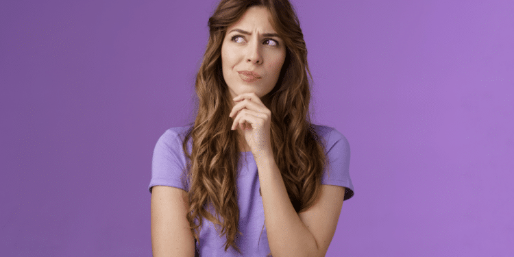 Mulher pensativa com expressão curiosa em fundo roxo.