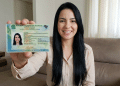 Mulher exibe nova carteira de identidade brasileira em casa.