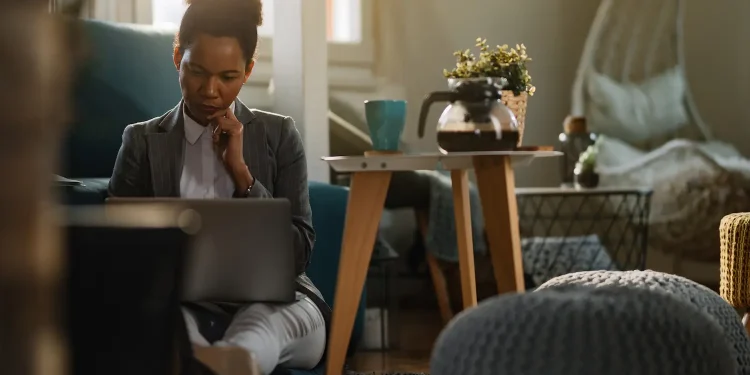 Pessoa em ambiente de trabalho remoto em casa usando notebook, simbolizando efeitos do home office sobre a saúde mental e o aumento do isolamento social.