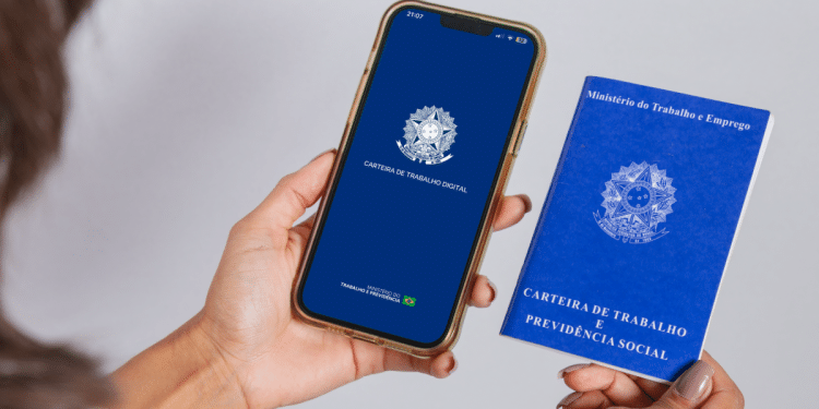 Mulher segura celular com aplicativo Carteira de Trabalho Digital aberto e carteira física azul ao lado.