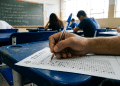 Mão masculina marcando gabarito de prova em sala de aula.