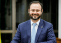 Ministro Paulo Pereira em gabinete oficial com bandeira nacional.