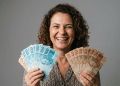 Mulher sorridente exibe notas de real em clima de conquista financeira.