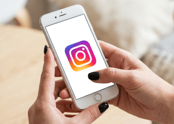 Pessoa com unhas pretas acessa o Instagram no smartphone.