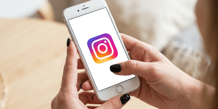 Pessoa com unhas pretas acessa o Instagram no smartphone.