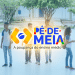 Grupo de jovens estudantes conversando em pátio escolar com logo Pé-de-Meia ao centro.