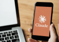 Logo do Claude exibido em smartphone ao lado de notebook.