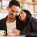 Casal sorridente aproveita momento juntos em cafeteria.