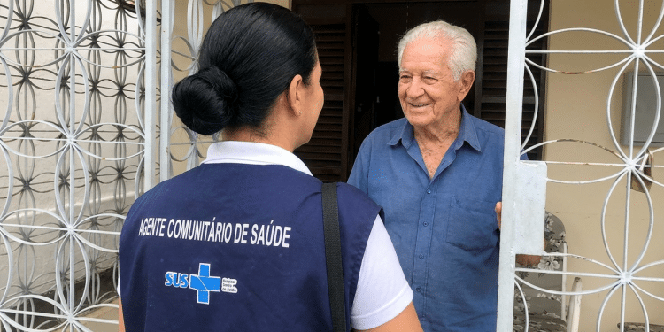 Visita domiciliar de agente comunitária de saúde do SUS atende idoso.