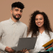 Professores sorridentes com laptop e cadernos sobre fundo bege.