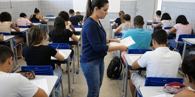 Mulher distribuindo prova em sala de aula.
