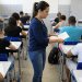 Mulher distribuindo prova em sala de aula.