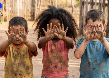 Crianças exibindo mãos sujas, remetendo ao trabalho infantil.