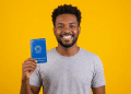 Jovem negro sorrindo exibe Carteira de Trabalho azul.