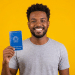 Jovem negro sorrindo exibe Carteira de Trabalho azul.