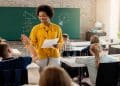 Imagem ilustrativa de uma professora em sala de aula com alunos, tema da matéria sobre como abreviar a palavra professora.