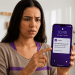 Mulher observa notificação do Nubank no celular com alerta de dívida registrada no CPF