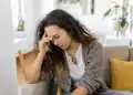 Mulher sentada no sofá com expressão preocupada, representando ansiedade, insegurança e dúvidas sobre si mesma.