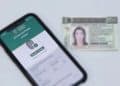 Celular exibindo o aplicativo e-Título com a mensagem "Biometria coletada" ao lado de uma carteira de identidade