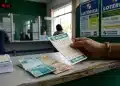 Apostador segura volante da Mega-Sena em casa lotérica, com cédulas de real sobre o balcão, em dia de apostas para prêmio de R$ 16 milhões.