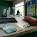 Apostador segura volante da Mega-Sena em casa lotérica, com cédulas de real sobre o balcão, em dia de apostas para prêmio de R$ 16 milhões.