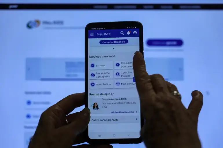 Pessoa utilizando o aplicativo Meu INSS em smartphone para consultar serviços e acompanhar solicitações relacionadas a benefícios previdenciários.
