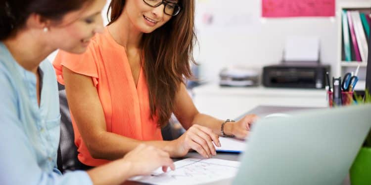 Duas profissionais analisam dados no escritório, representando os cursos que aceleram a entrada no mercado de trabalho