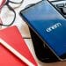 Celular exibindo a logo do Enem na tela ao lado de teclado, óculos, caderno e lápis, em referência ao resultado do atendimento especializado do Enem 2026