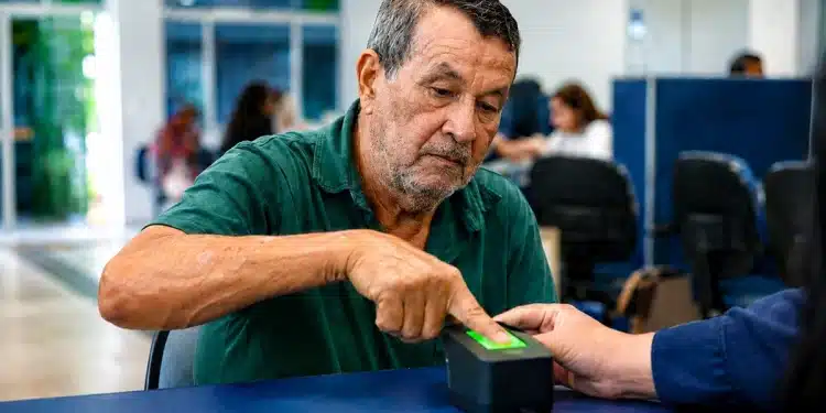Segurado do INSS realiza cadastro de biometria em scanner digital durante atendimento, representando as novas regras para o cadastramento biométrico.