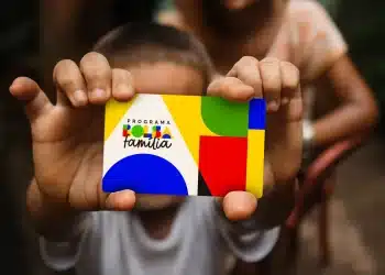 Criança segurando cartão do Bolsa Família durante pagamento do benefício social.