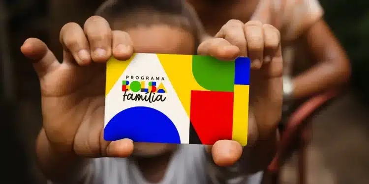 Criança segurando cartão do Bolsa Família durante pagamento do benefício social.