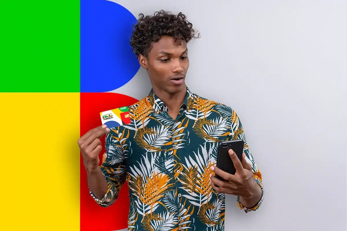 Beneficiário do Bolsa Família segurando cartão do programa enquanto consulta o celular